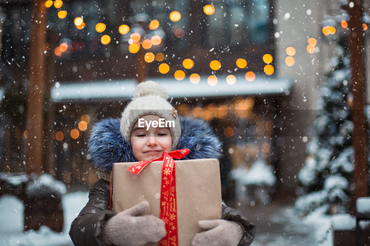 Portrait of smiling girl holding present standing outdoors