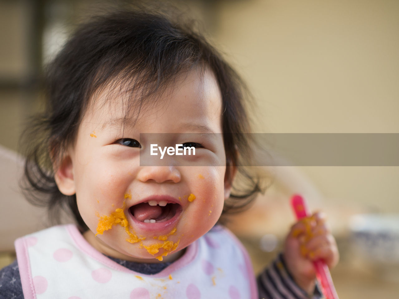 Close-up portrait of cute baby girl eating mashed potatoes at home