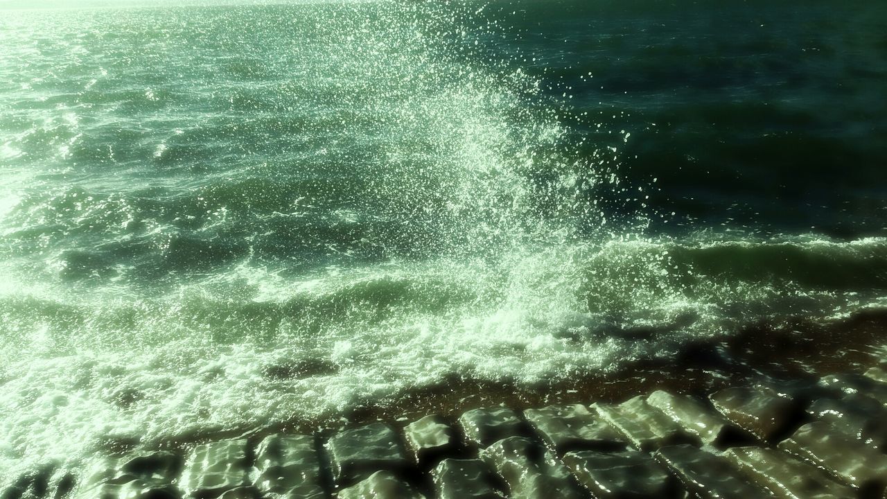 Waves hitting rocky shore by sea