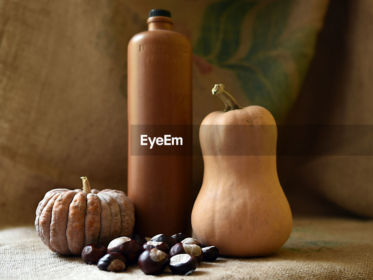 Close-up of chestnuts and pumpkins by bottle on table