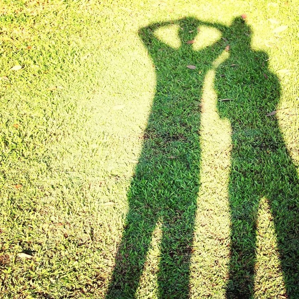 Shadow of family on grassy field during sunny day