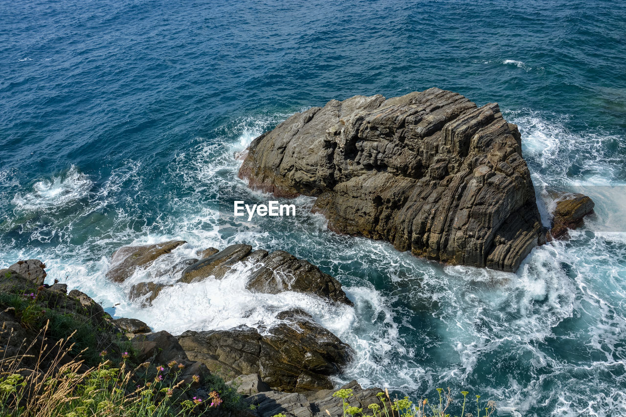 HIGH ANGLE VIEW OF WAVES BREAKING ON ROCKS