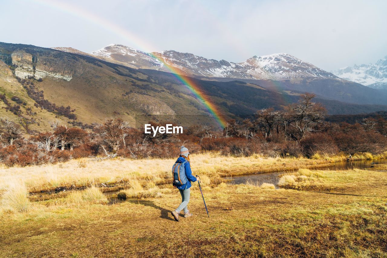 Woman walking on field against mountains during winter