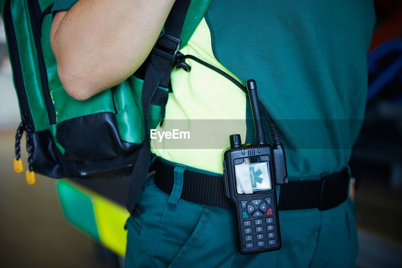 Midsection of female paramedic with walkie-talkie on belt in parking lot