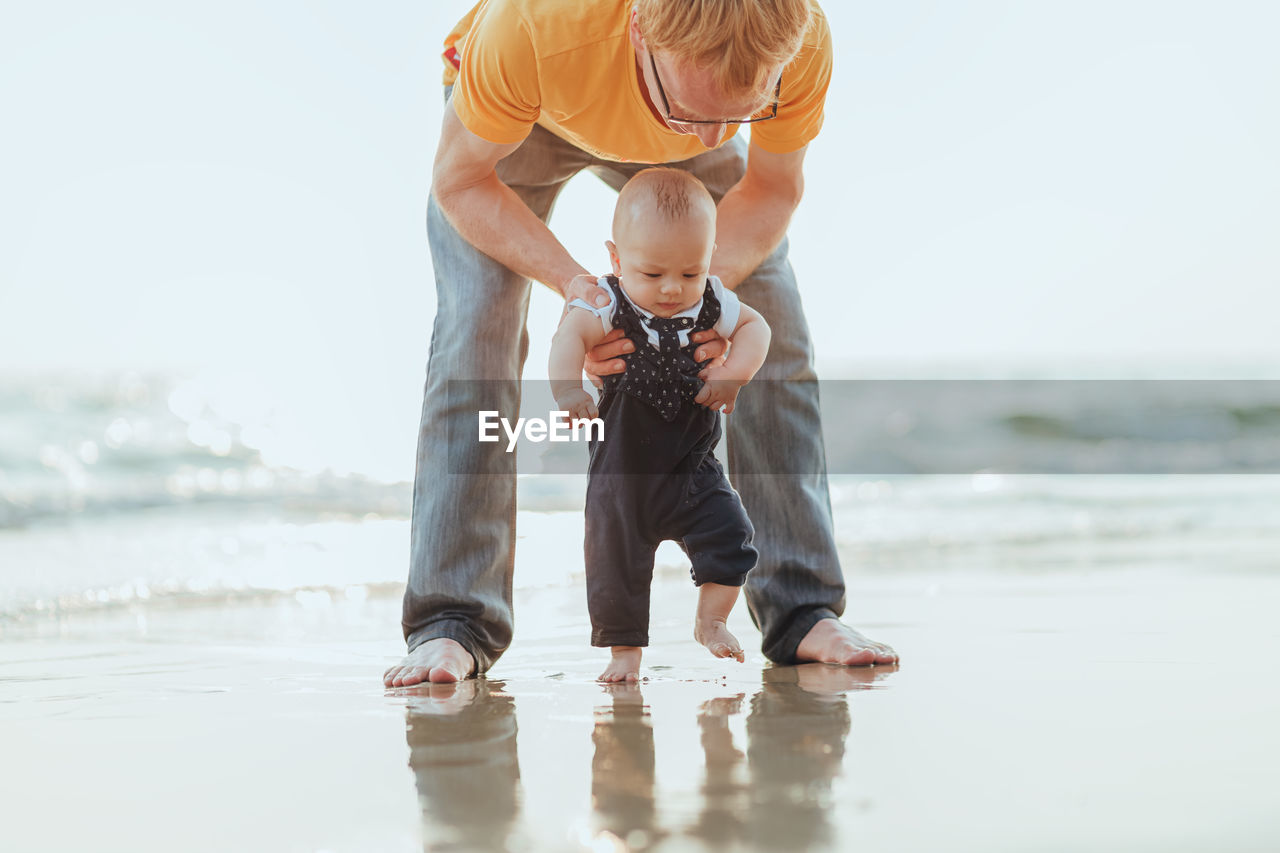 Full length of father and son at sea shore