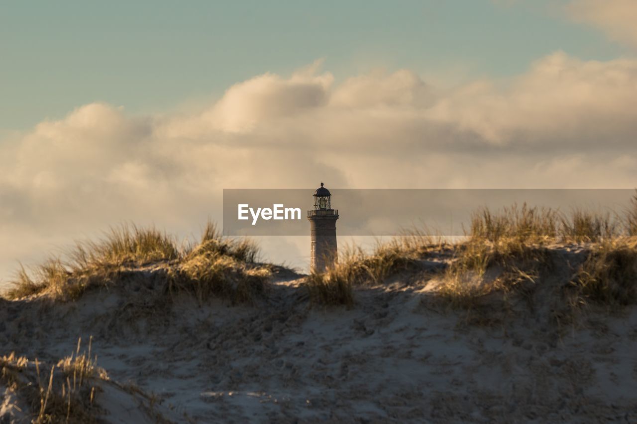 Lighthouse by sea against sky during sunset