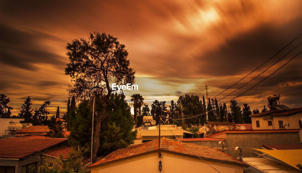Houses and trees against sky during sunset