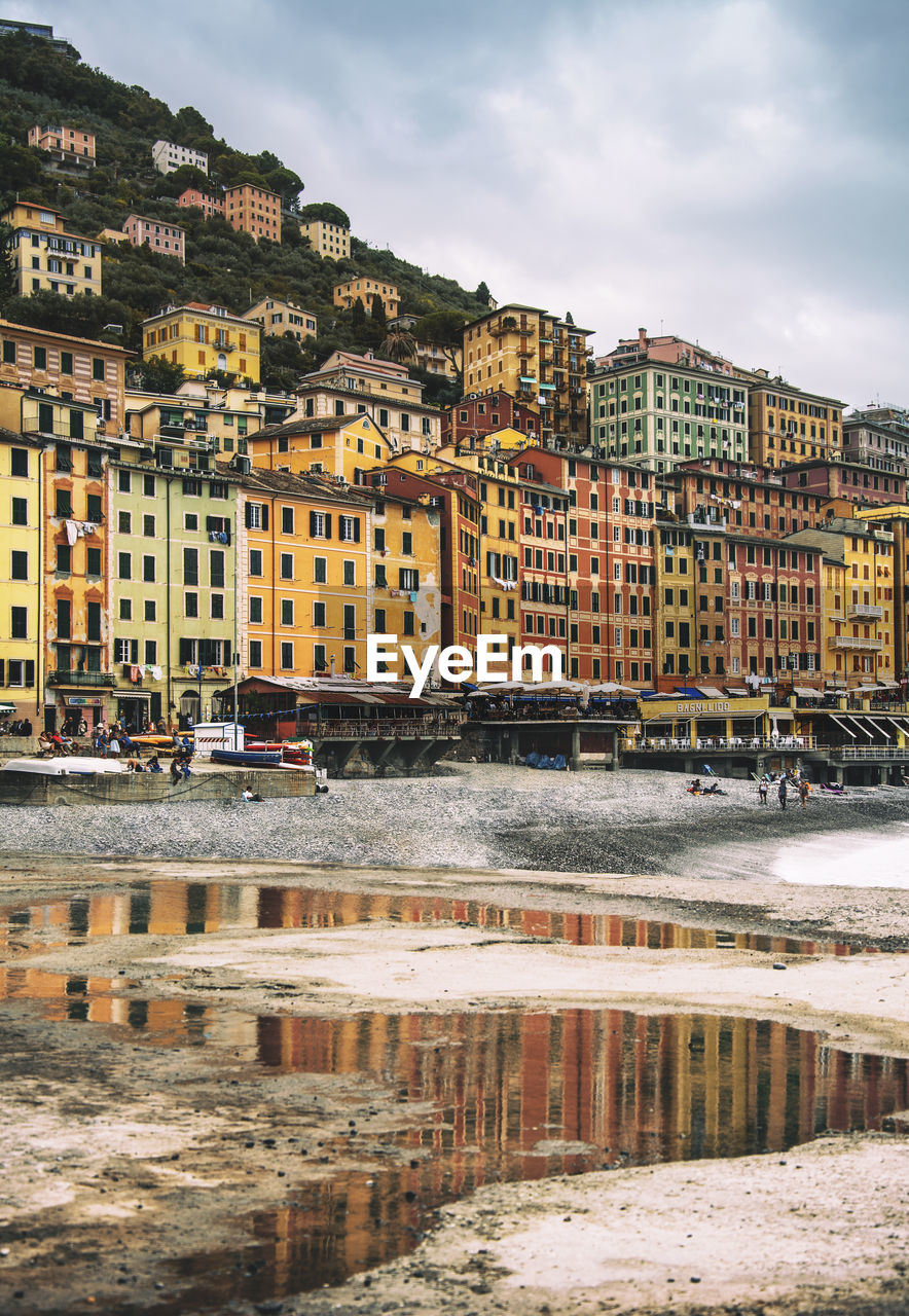 Buildings by river against sky in city