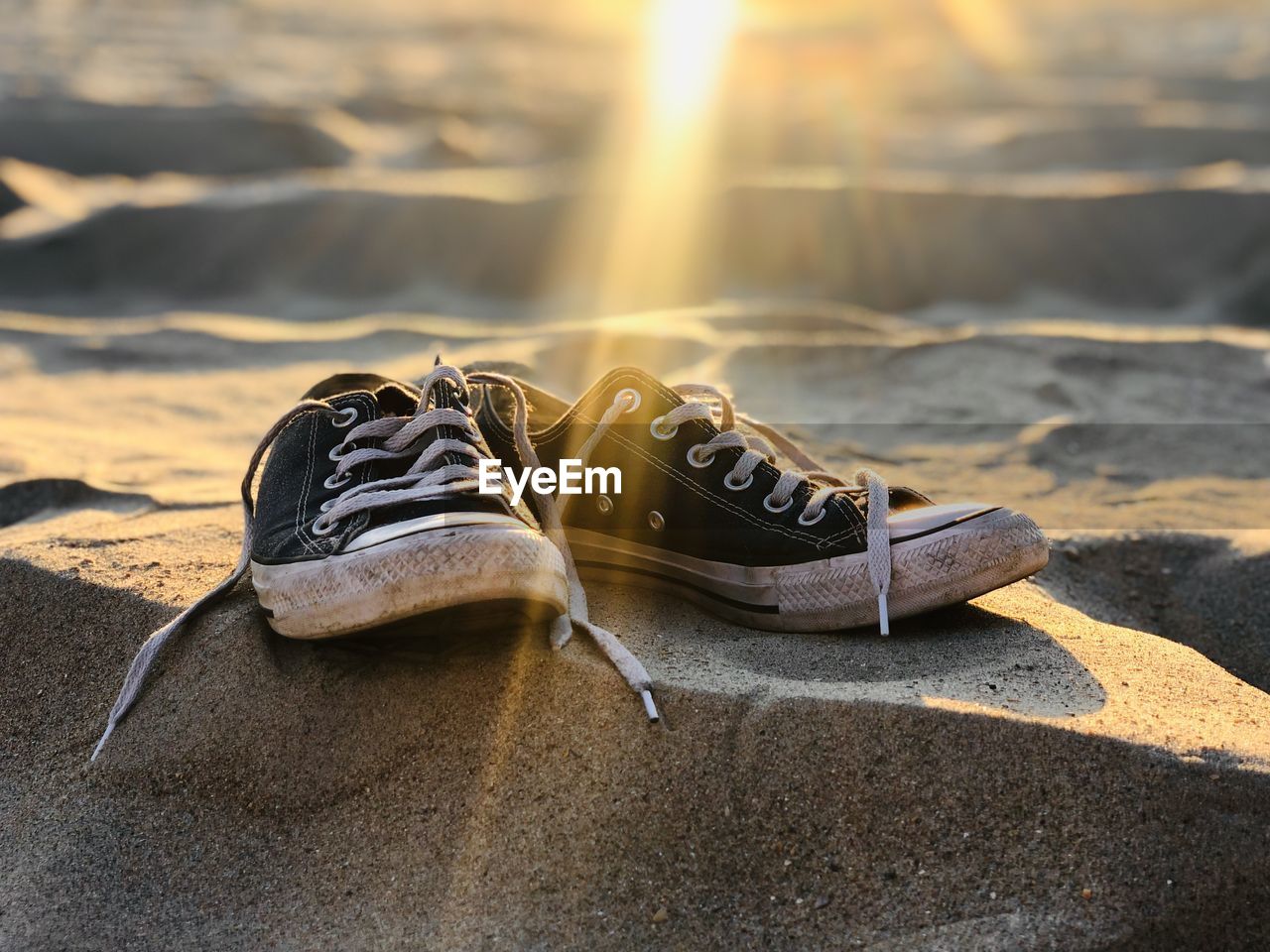 footwear, shoe, sunlight, nature, yellow, pair, sneakers, land, black, spring, white, sand, beach, brown, outdoors, sunset, no people, sun, day, absence, focus on foreground, water, close-up, lens flare, sports