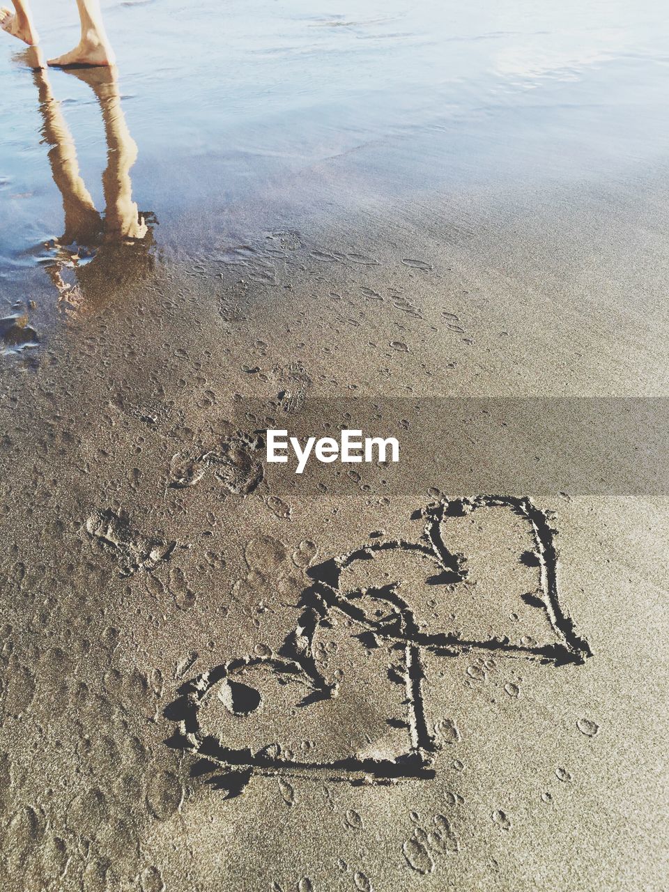 Low section of person on sand at beach - two hearts
