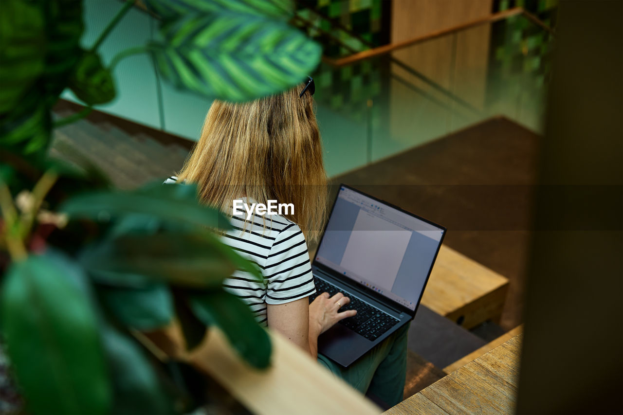 Woman using laptop in coworking. female freelancer typing on laptop keyboard. online work in cafe