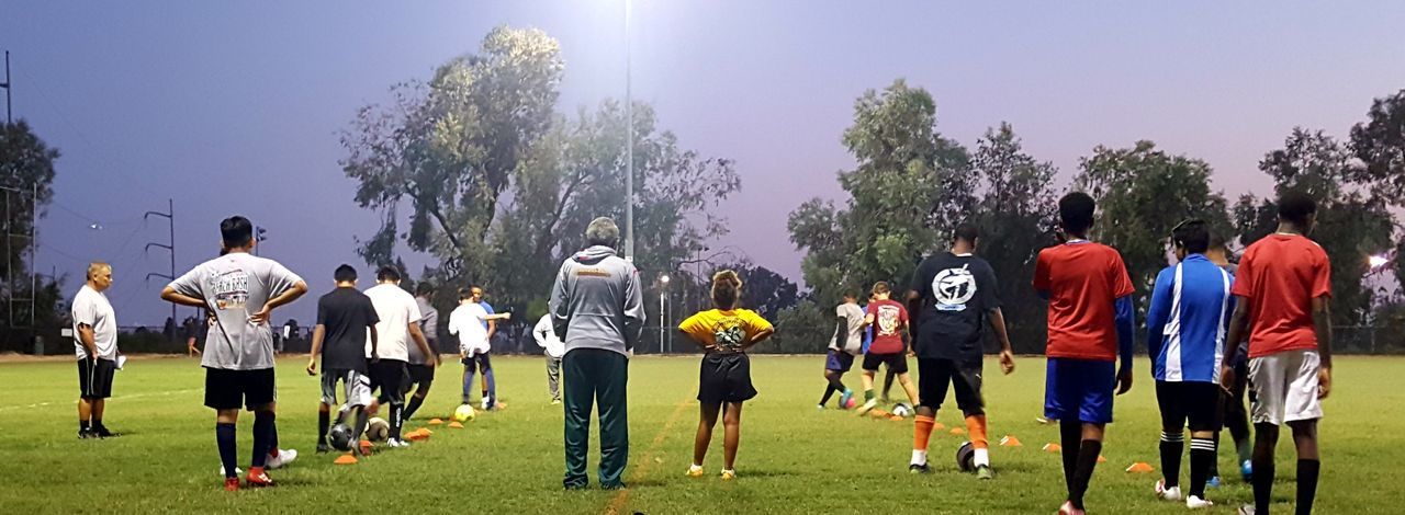 REAR VIEW OF MEN STANDING ON FIELD