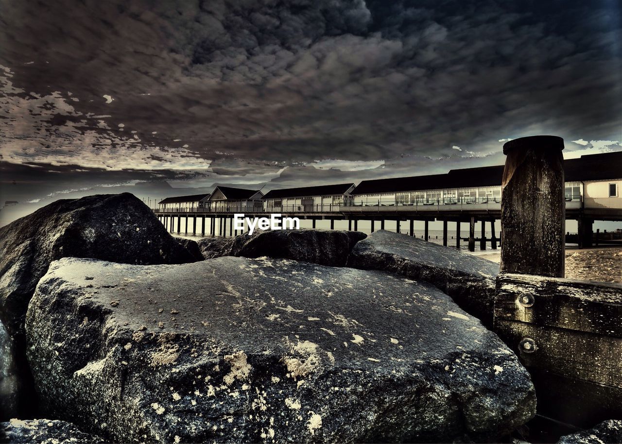 Pier in sea against cloudy sky