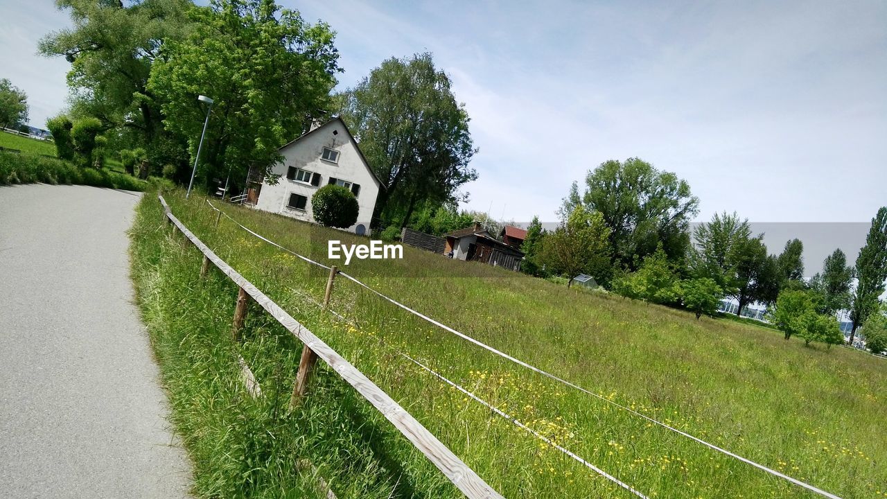 Road by grassy field against sky