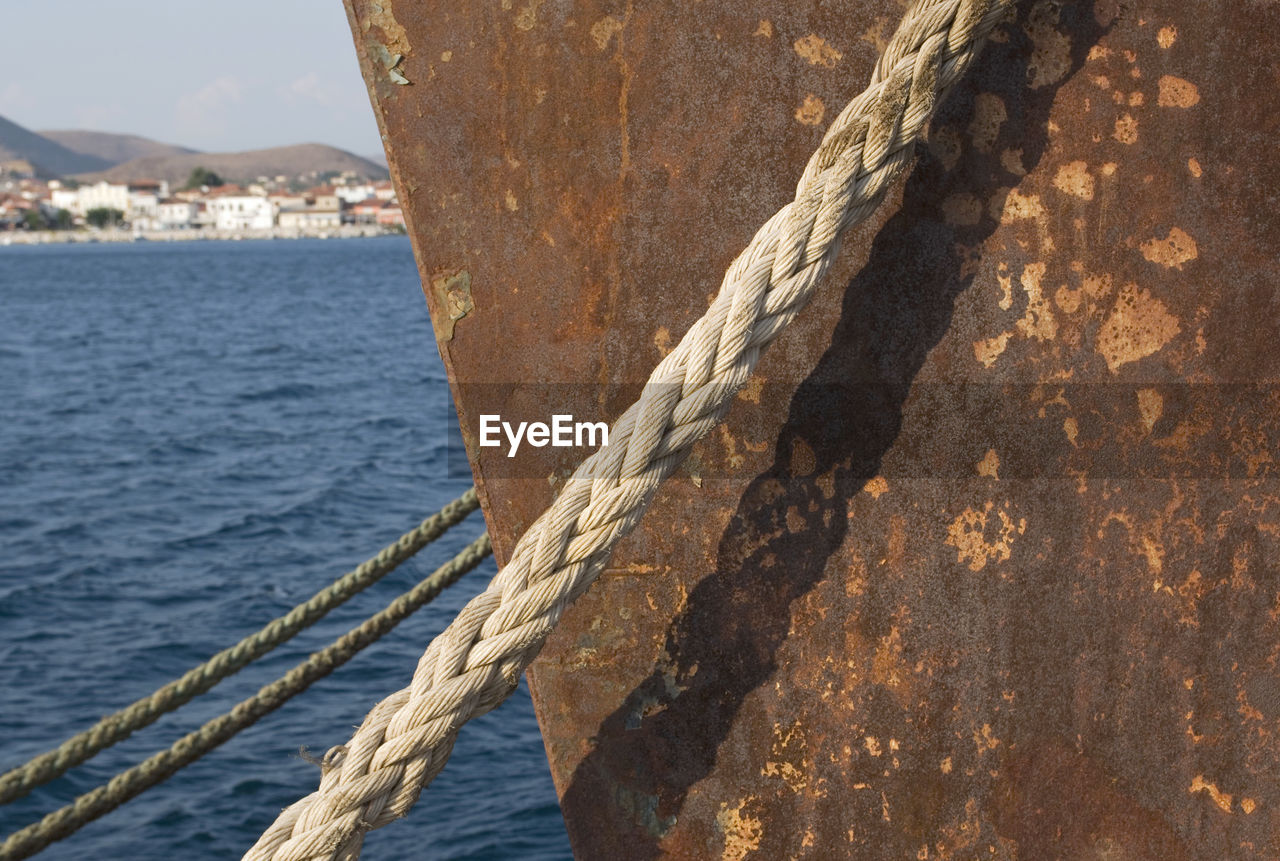 Close-up of rope against rusty nautical vessel on sea