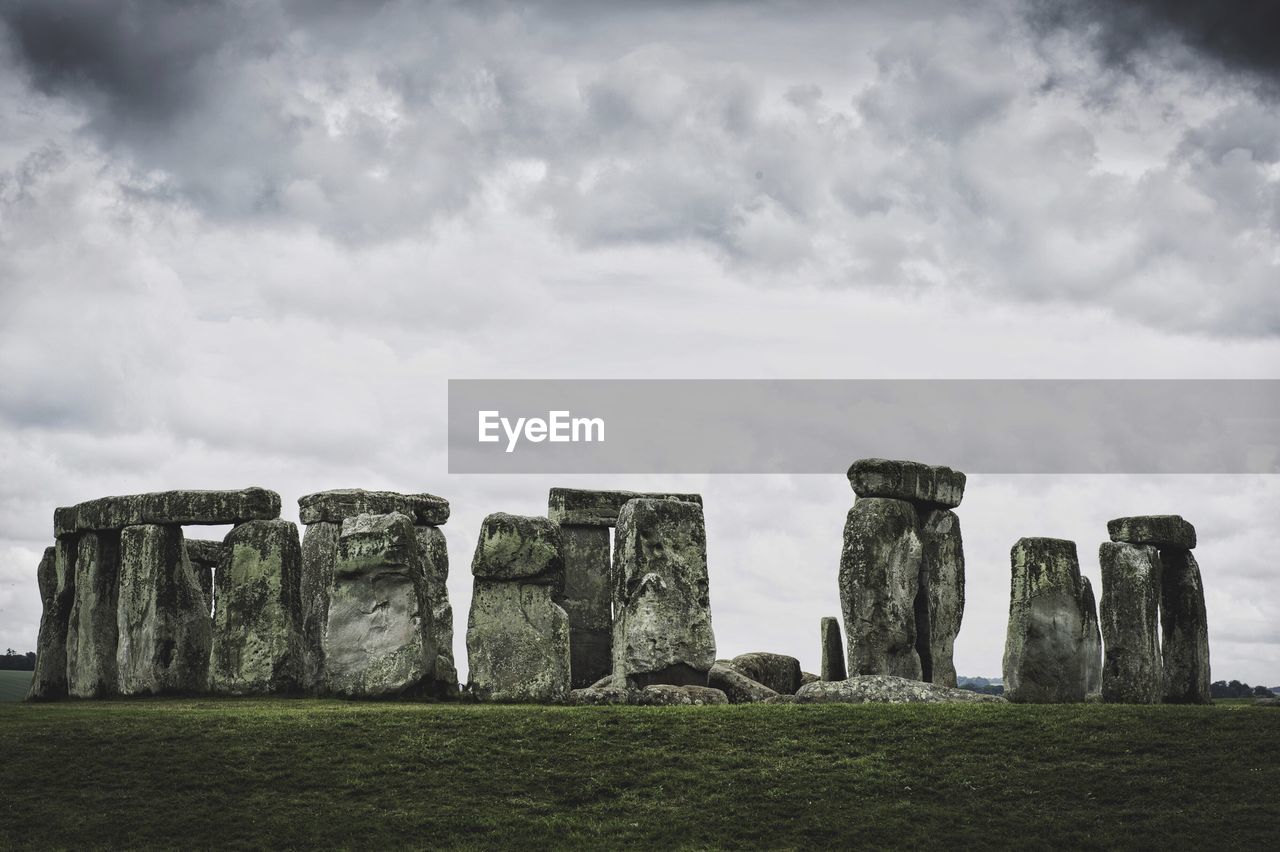 Old ruins on field against cloudy sky