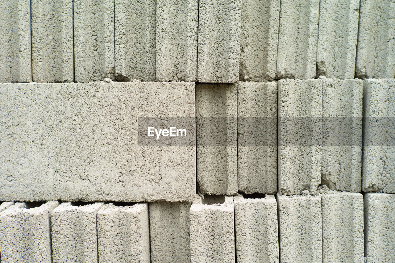 Close-up cement grey bricks out of the pile with blurred background at the construction site. 