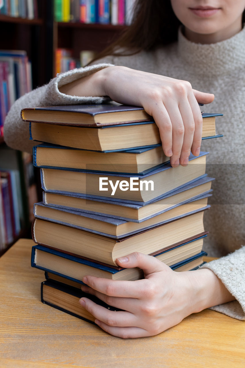 Young woman holds a stack of books close up person