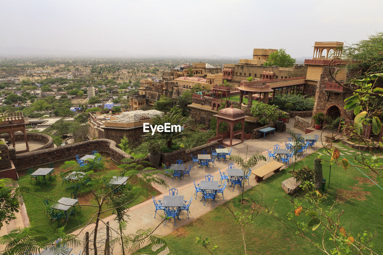 Empty chairs and table at neemrana fort-palace against sky