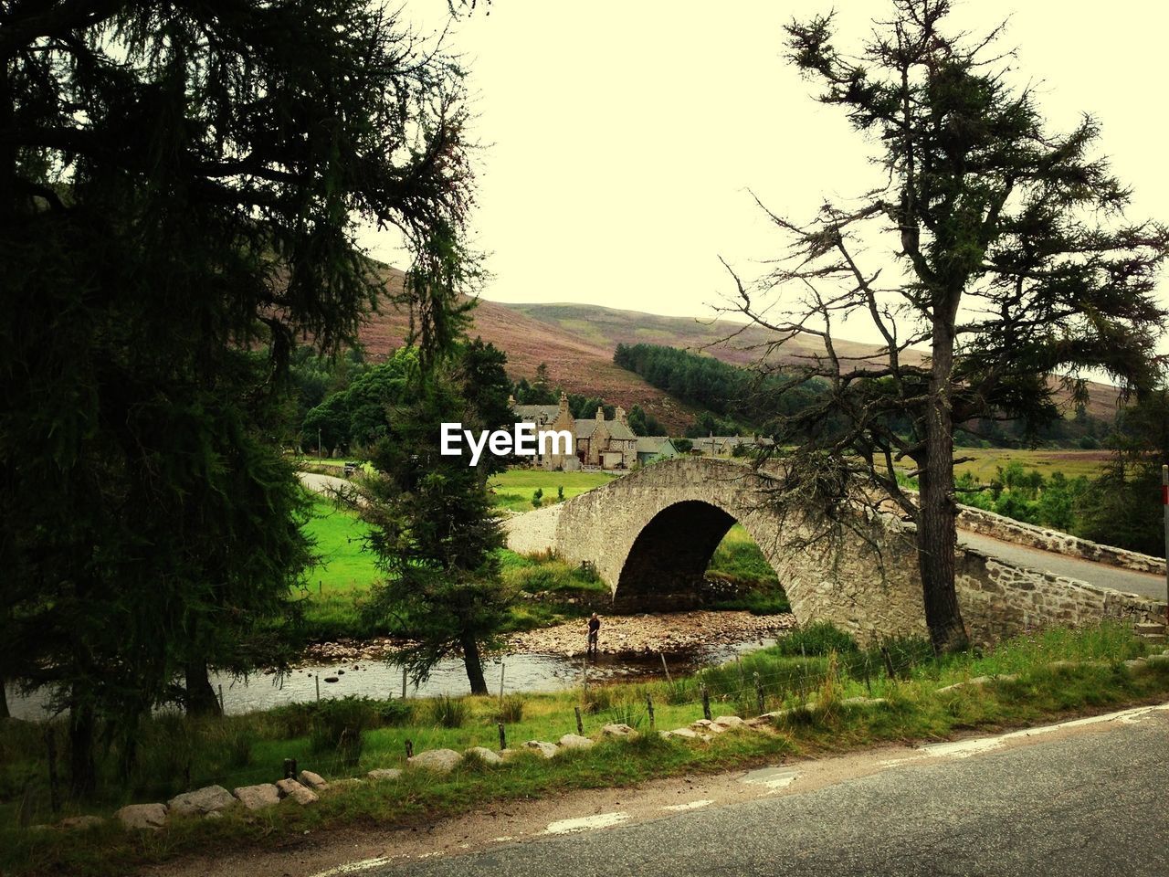 Arch bridge over stream against sky