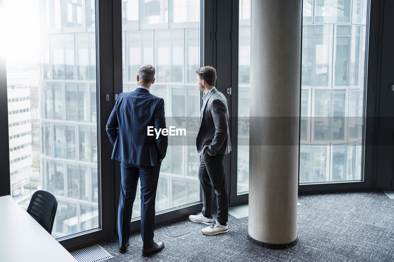 Businessman and entrepreneur looking through window in office