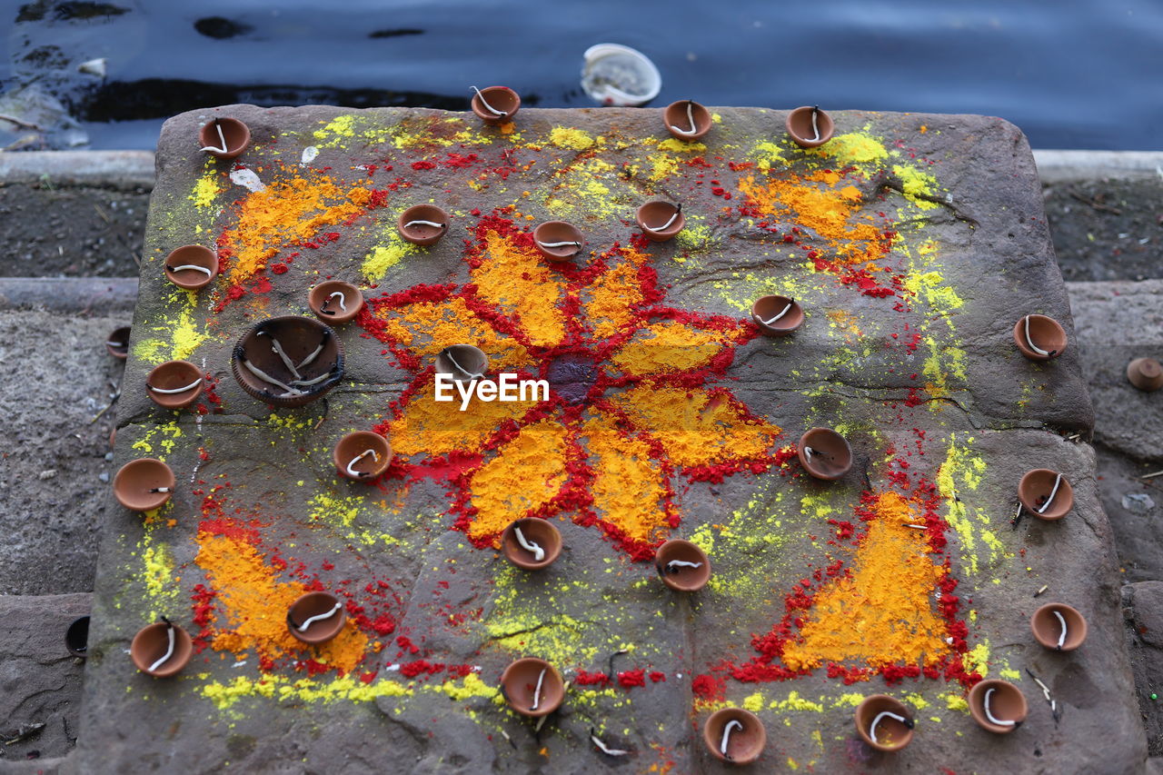 High angle view of powder paint with diyas by river