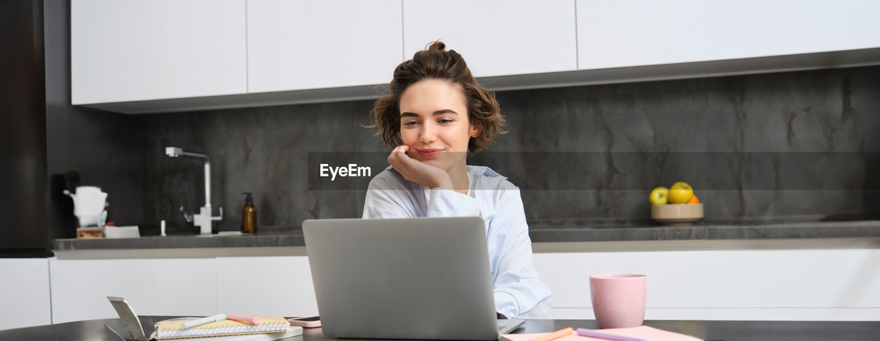 portrait of young woman using laptop at home