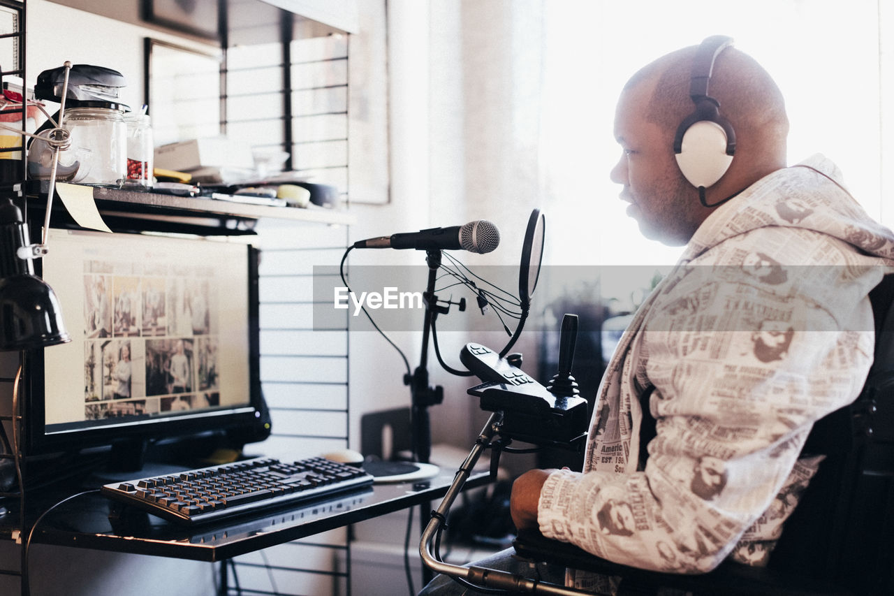 Side view of disabled man wearing headphones while looking at computer