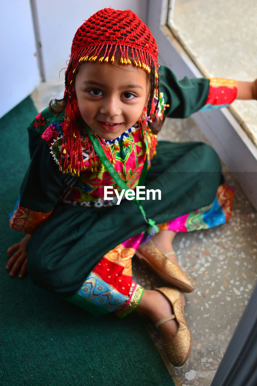 High angle portrait of girl in traditional clothing sitting at home