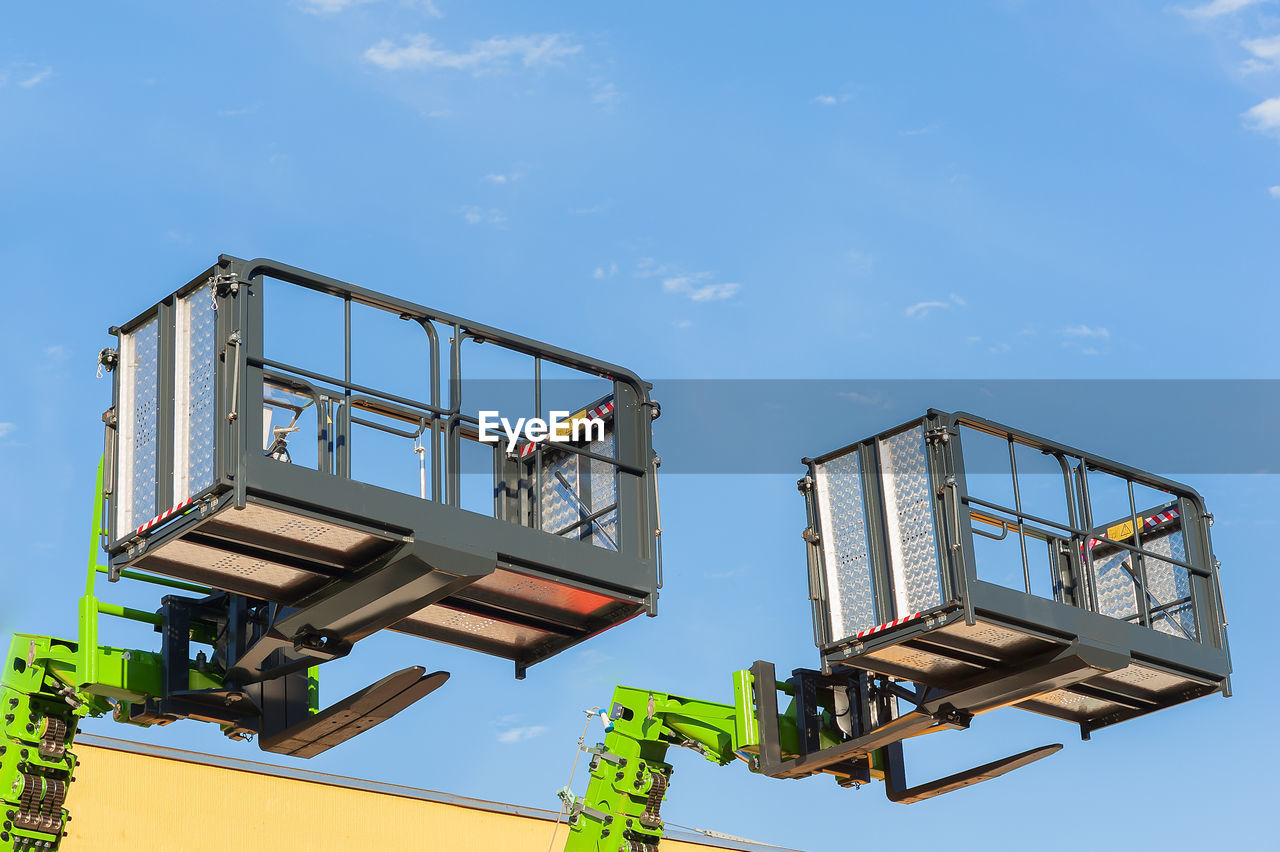Low angle view lifting platforms against sky