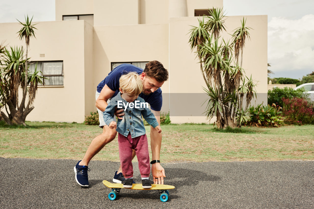 Father and son playing on skateboard outdoors