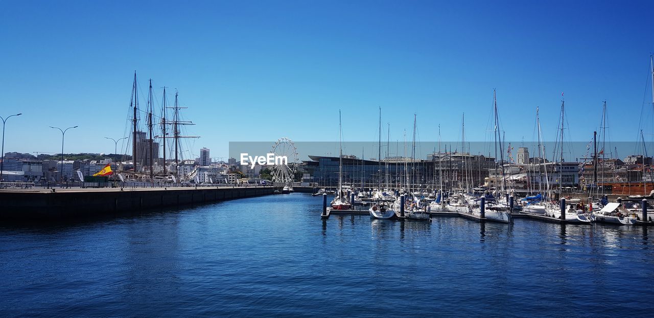 water, nautical vessel, transportation, harbor, dock, mode of transportation, marina, sky, sailboat, sea, port, pole, vehicle, mast, architecture, nature, boat, moored, blue, ship, no people, clear sky, reflection, travel, channel, bay, pier, city, watercraft, travel destinations, sailing, day, outdoors, waterfront, sailing ship, built structure, building exterior, tall ship, commercial dock, infrastructure