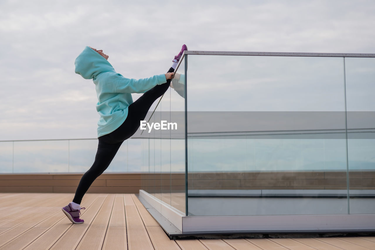 Side view of athlete stretching on glass railing