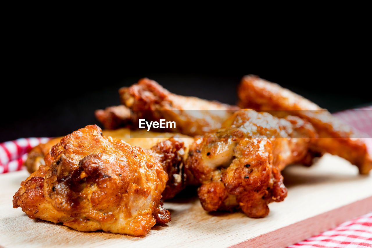 Close-up of barbecue meat on cutting board against black background