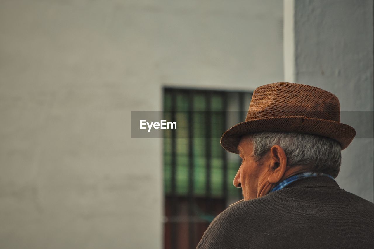 Rear view of senior man wearing hat against building