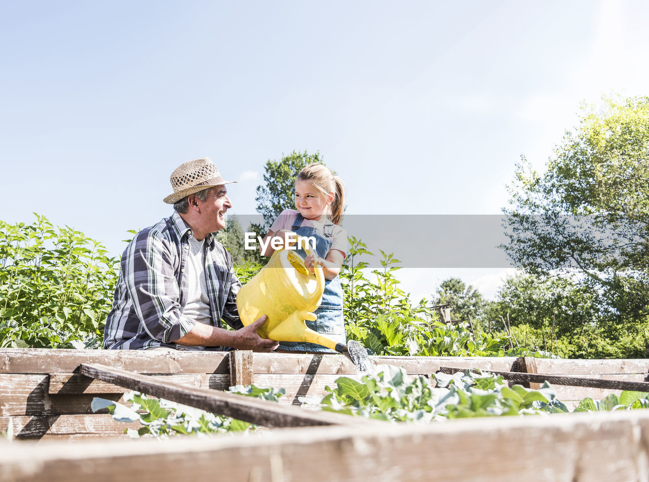 Grandfather and granddaughter in the garden watering plants