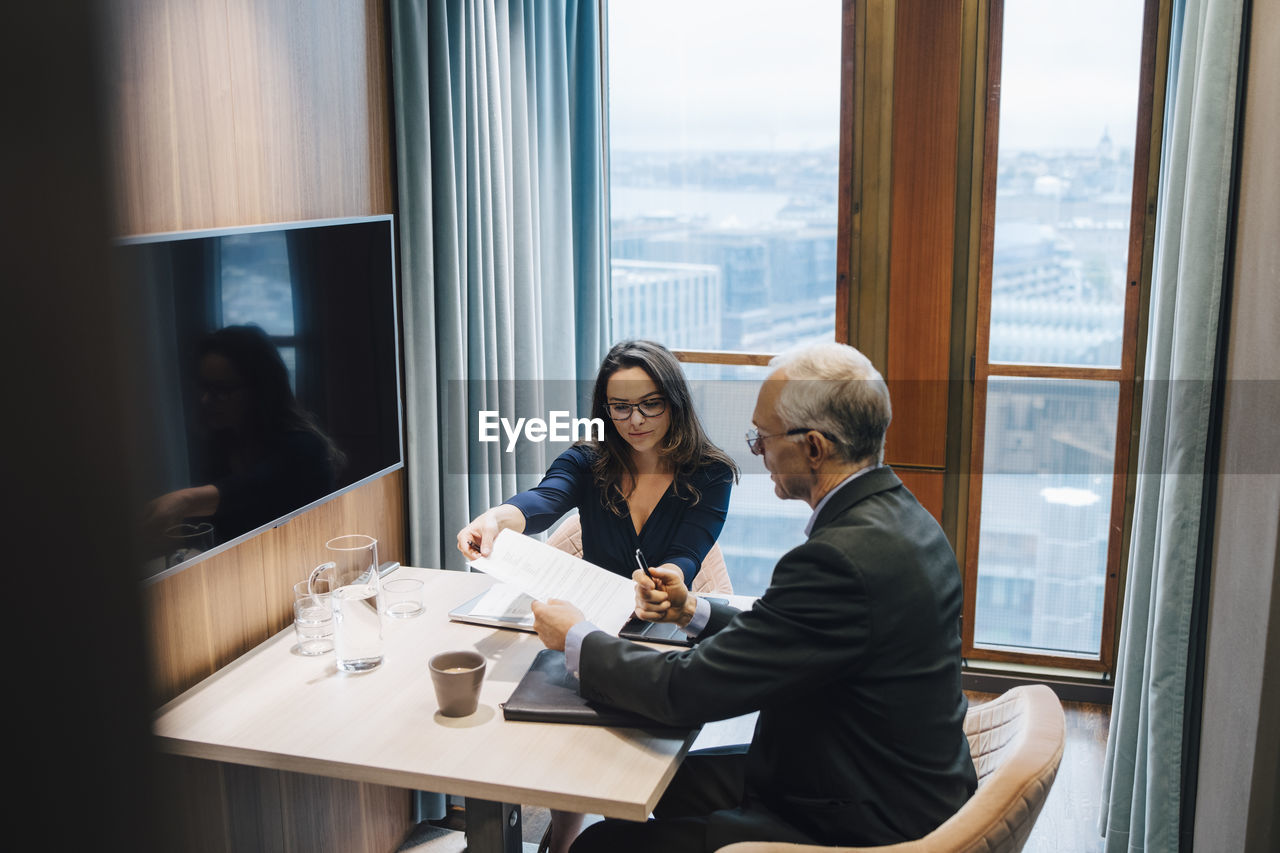 Female entrepreneur discussing with male colleague over document in board room at office