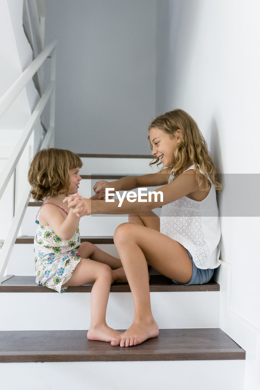 Side view of happy siblings playing on steps