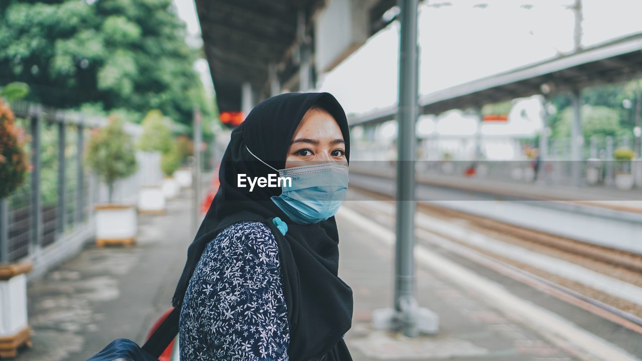 Portrait of young woman standing at railroad station