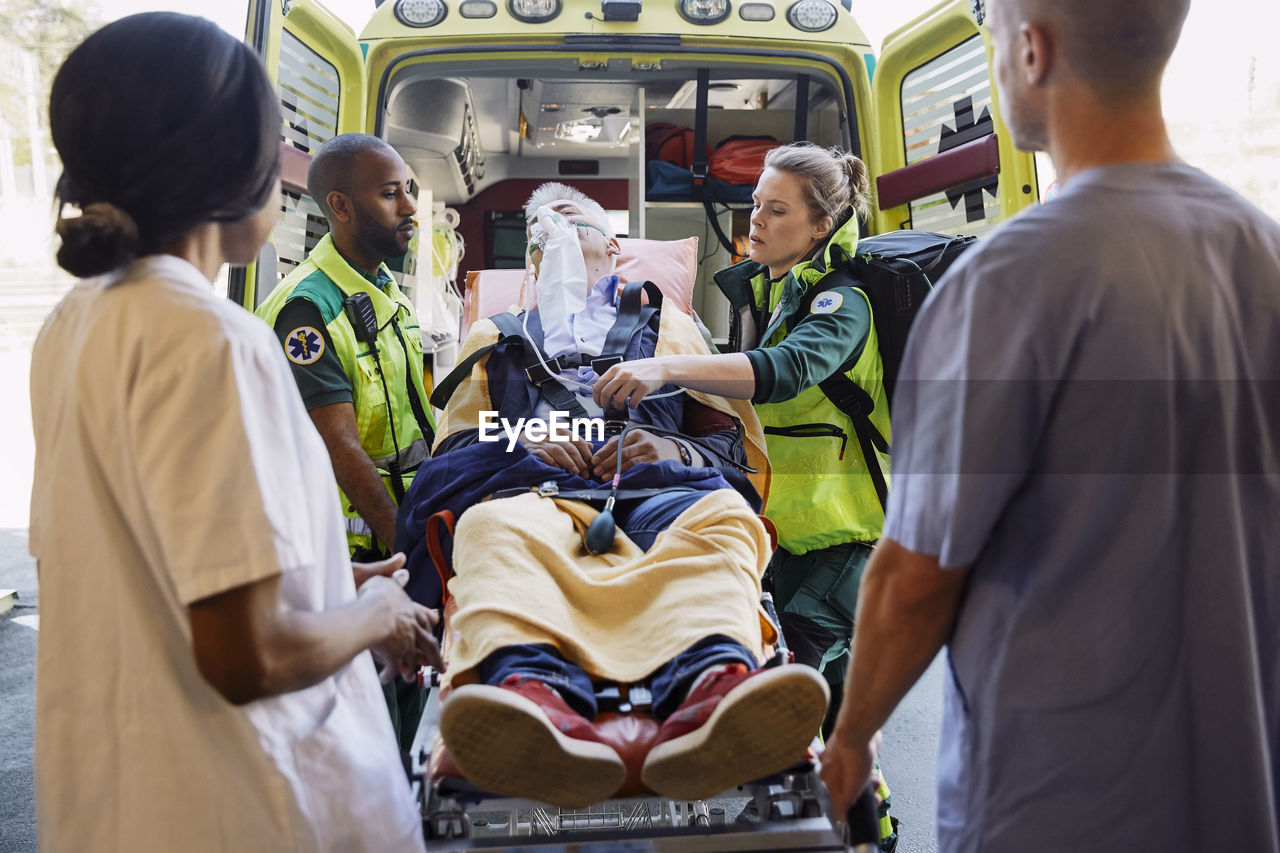 Medical professionals looking at paramedics with patient against ambulance