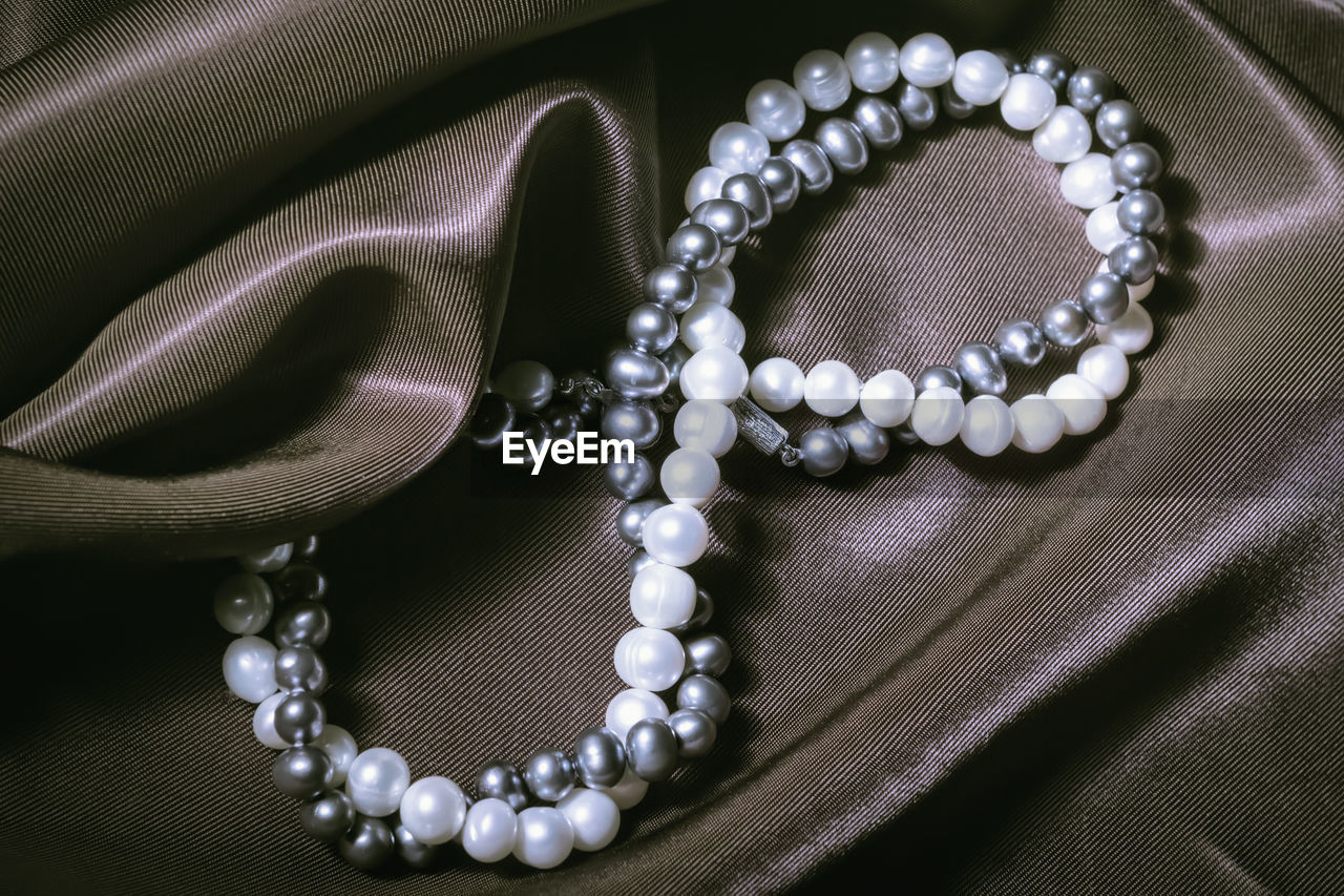 Necklaces of white and black pearls in the form of an infinity sign or figure eight on silk. present