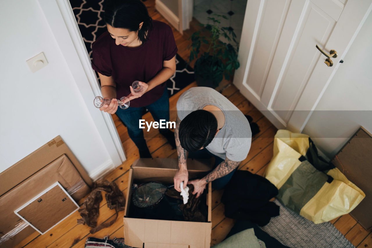 High angle view of couple unpacking box at home