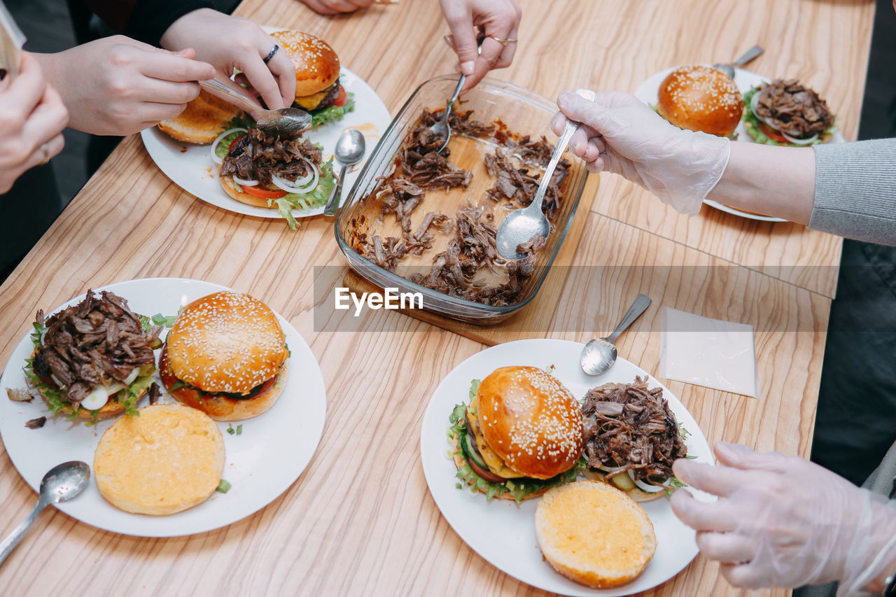 Burgers with beef and vegetables, the cooking process, hands collecting the burger.