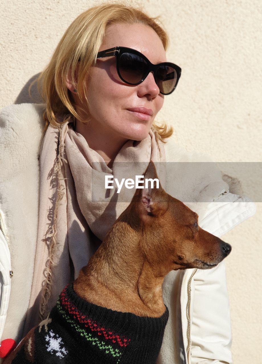 Close-up of woman wearing sunglasses with dog standing outdoors