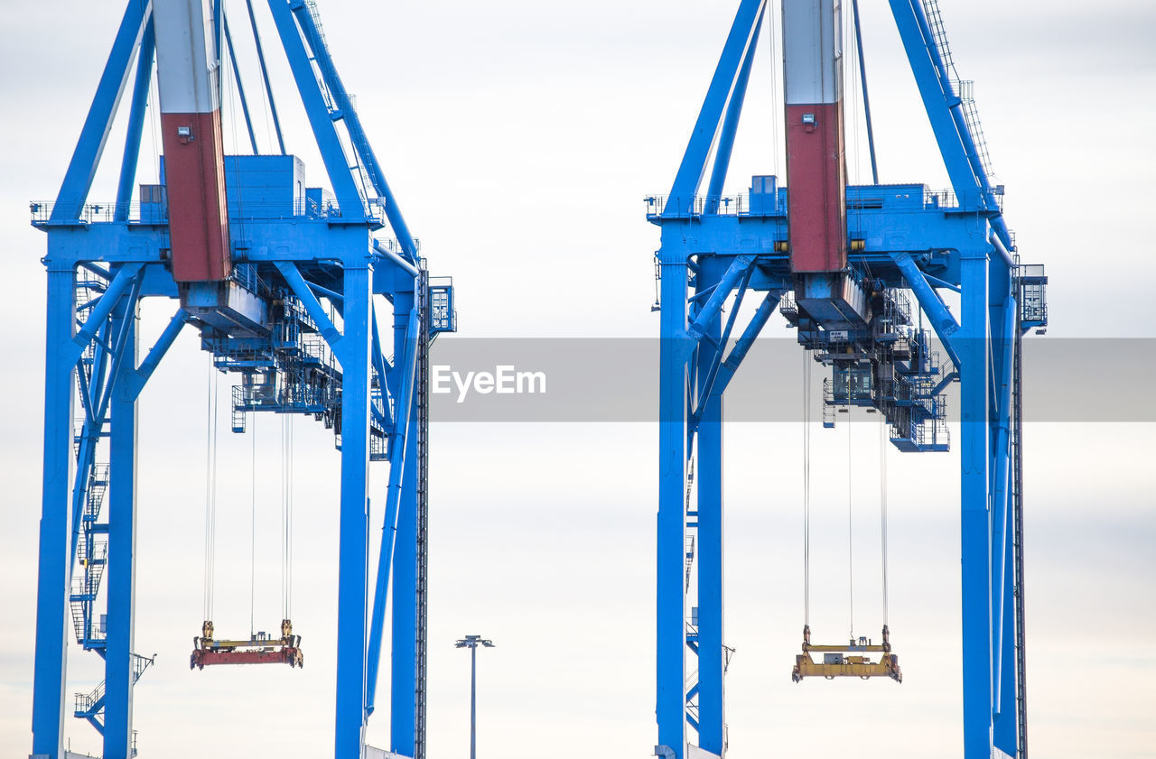 Low angle view of cranes against sky