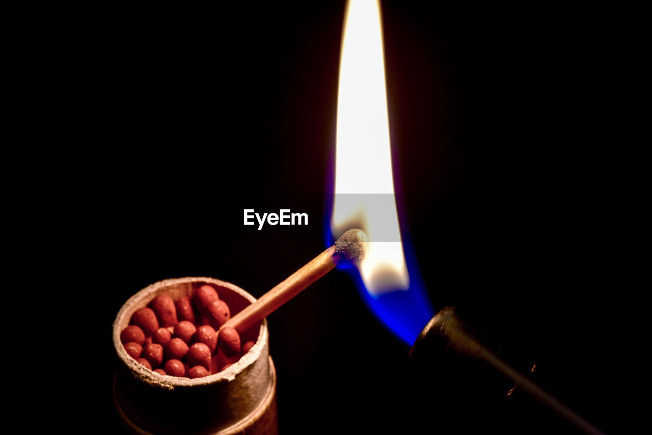 Close-up of igniting matchstick against black background