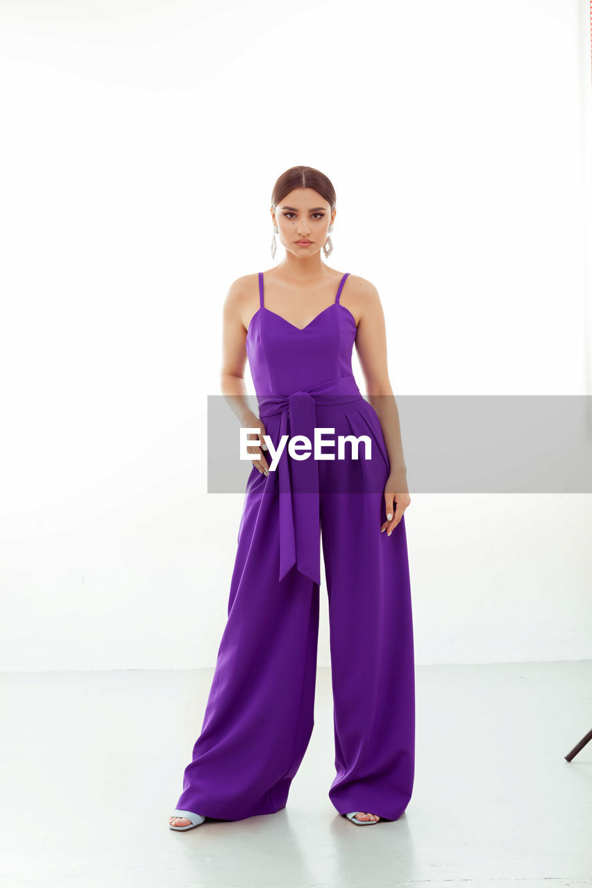 purple, full length, gown, fashion, one person, women, portrait, clothing, adult, violet, young adult, looking at camera, indoors, dress, magenta, studio shot, elegance, bridal clothing, wedding dress, standing, formal wear, female, front view, pink, brown hair, satin, lavender, person, smiling, cocktail dress, glamour, white background, spring, hairstyle, evening gown