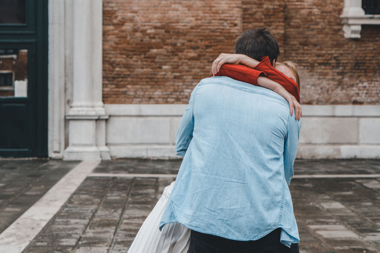 REAR VIEW OF COUPLE WALKING ON BUILDING