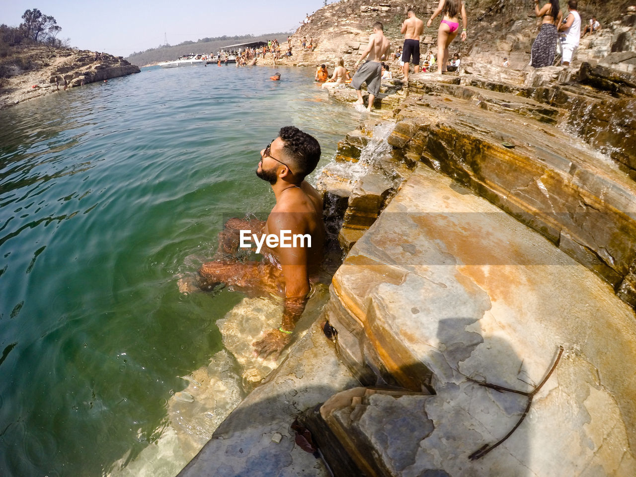 MAN STANDING ON ROCK AT SHORE