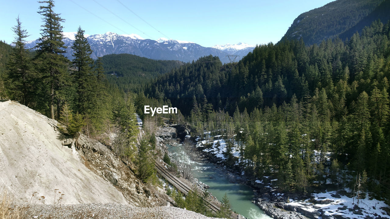 A view of a creek situated beside cp railway at a snow covered valley with mountains